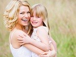 Mother holding daughter outdoors smiling