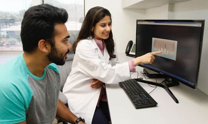 Dr. Bhave showing a patient a dental implant on a computer monitor