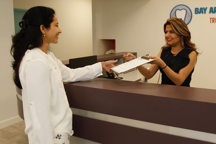 Receptionist gives clipboard to patient