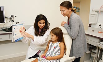 Dr. Bhave educating child patient. Mother watching