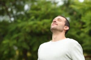 Man closes his eyes and breathes in deeply, feeling relieved after his TMJ and airway treatment at the dentist