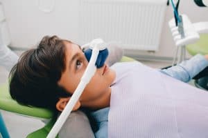 Little boy in the dentist's chair, with a mask over his nose to deliver dental sedation