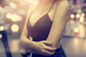 Woman folds her arms, her low-cut top showing off her breast augmentation results
