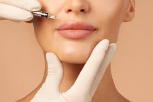 Woman smiles as her doctor injects Juvederm and Radiesse