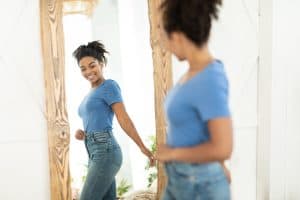 Woman looking in the mirror considering plastic surgery in Miami, FL