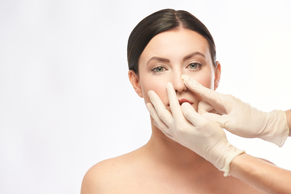 Plastic surgeon examining woman's nose before rhinoplasty