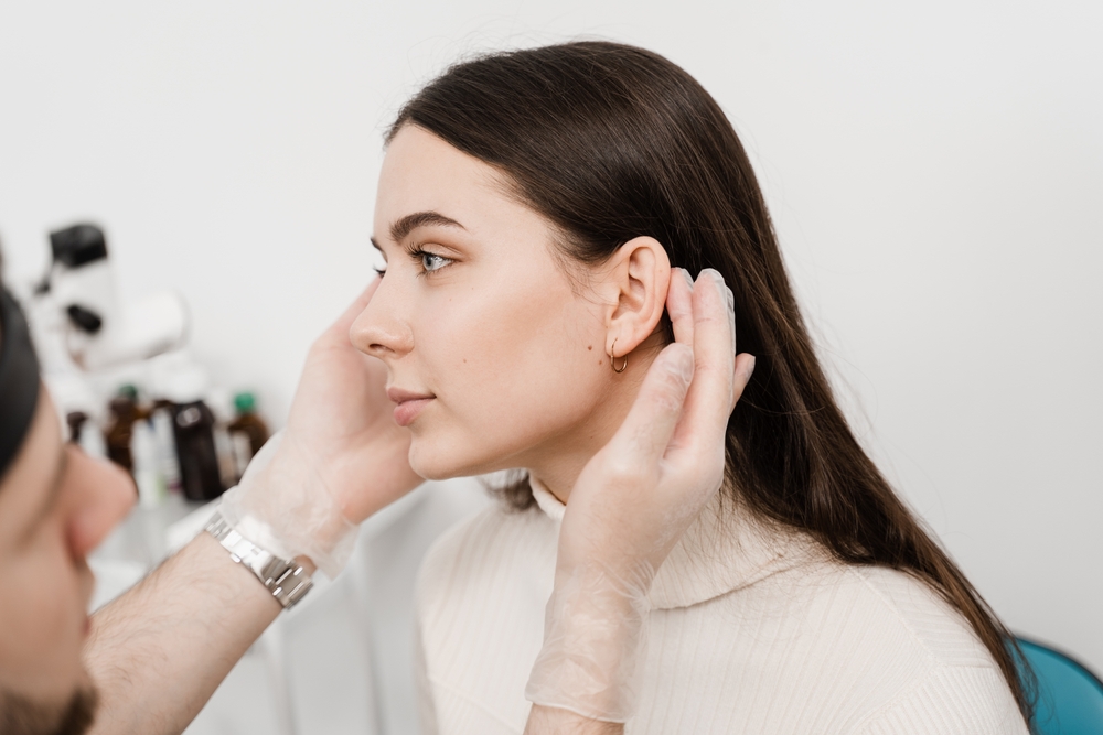 Doctor examining woman's ears for otoplasty in Westchester County, NY