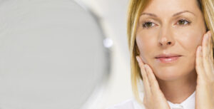 Woman looking in the mirror contemplating a facelift in Westchester County