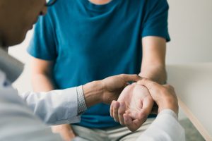 Physical therapist holds a patient's wrist