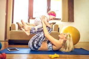 Beautiful woman in yoga pants, working out with her toddler following a mommy makeover