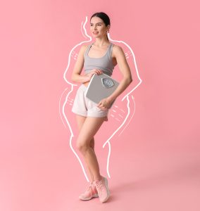 Pretty young woman holds a scale following her weight loss and lower body lift