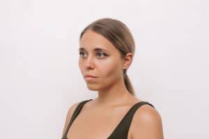 Young woman looks sad after weight loss caused facial hollowing