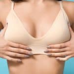 Young woman pushes her breasts out with her hands before a fat transfer breast augmentation in Cleveland