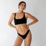 Smiling woman in black athletic wear standing with her hands on her hips, illustrating body contouring after weight loss.